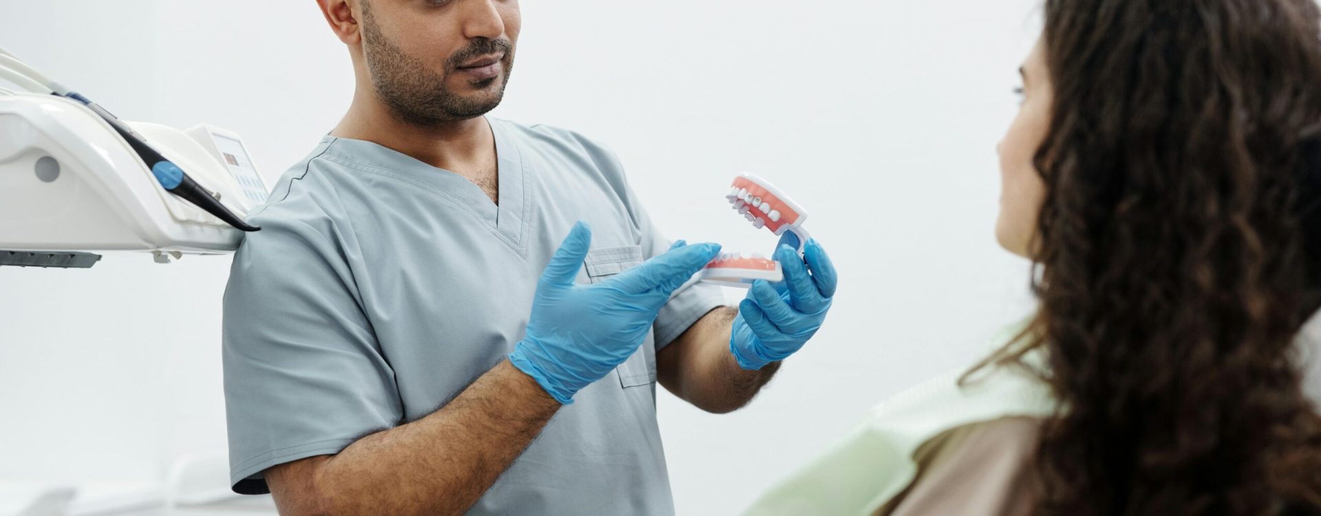 Dentist showing a dental model to a patient in a clinical setting.